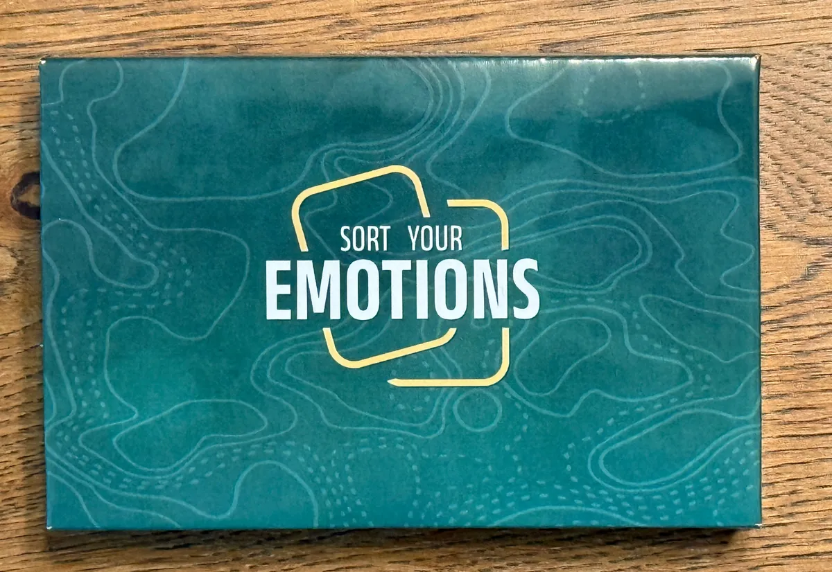 The closed deck box: teal with topographic contour lines and the Sort Your Emotions logo